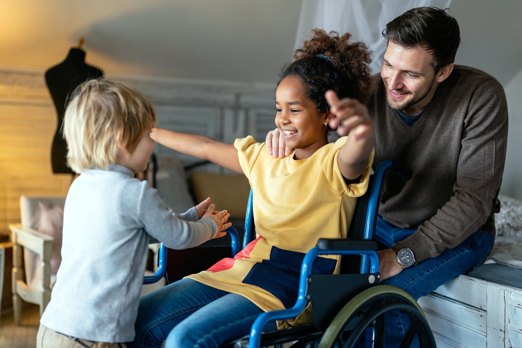 Happy multiethnic family. Smiling little girl with disability in wheelchair at home